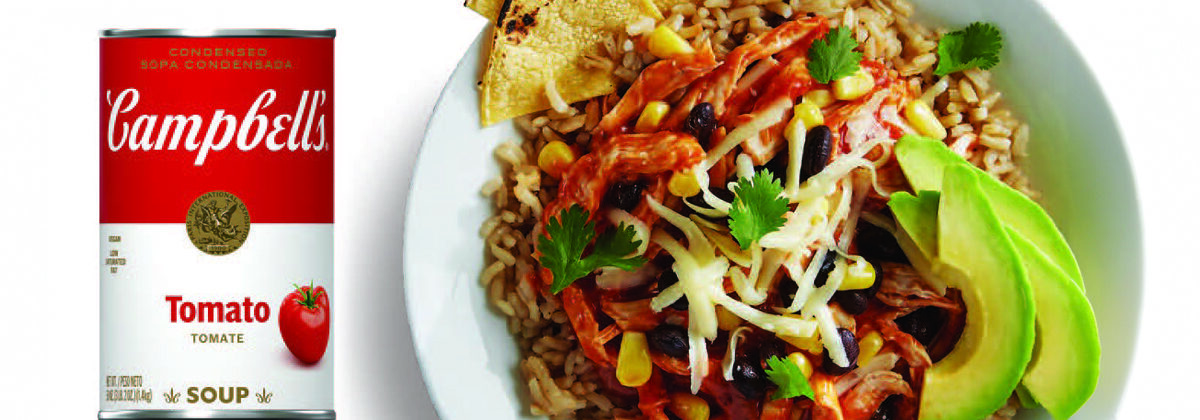 can of campbell's tomato soup beside a white bowl of cooked rice, chicken, black beans, corn, cheese, avocado