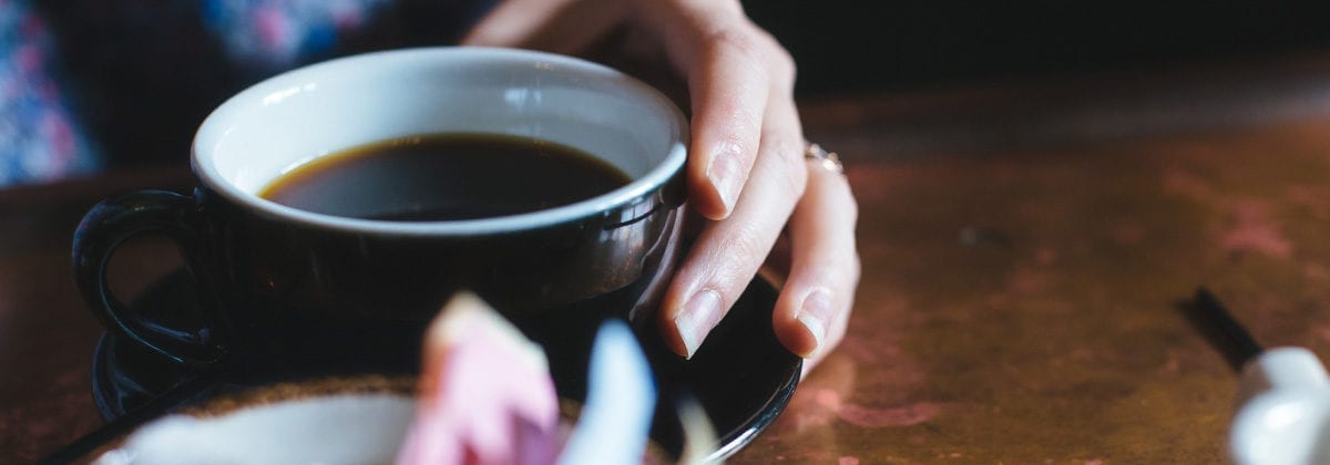 hands holding mug with black coffee