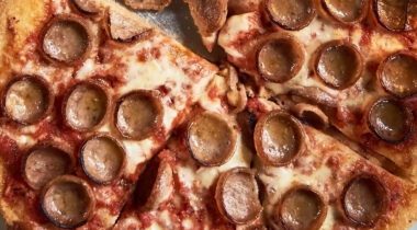 cooked cupped sausage slices on a pizza