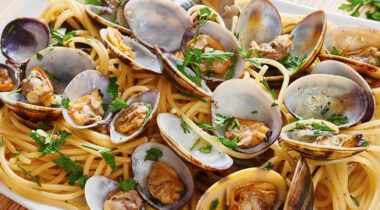 cooked clams and herbs on a plate with linguini noodles